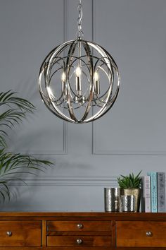 a chandelier hanging from the ceiling in a room with grey walls and wooden furniture