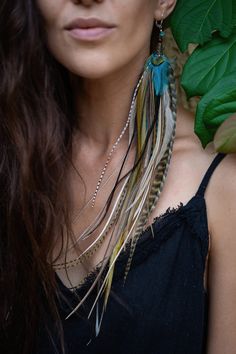 a woman with long brown hair wearing a feather necklace and matching earrings on her neck