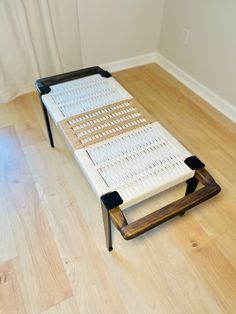 a white bed frame sitting on top of a hard wood floor next to a window