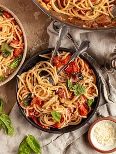 two pans filled with pasta and sauce on top of a table