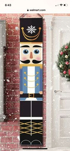 a christmas door hanger with a nutcracker in front of a brick wall