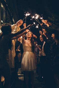 a group of people holding sparklers in the air with their hands and eyes open