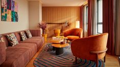 a living room filled with furniture next to a window covered in curtains and drapes