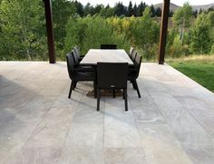 a table and chairs on a patio with trees in the background