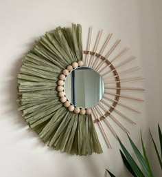 a mirror that is on the wall next to a potted plant and some sticks