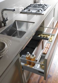 an open drawer in the side of a kitchen counter next to a stainless steel sink