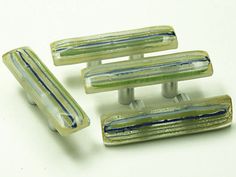 three pieces of glass sitting next to each other on a white surface with blue and green stripes