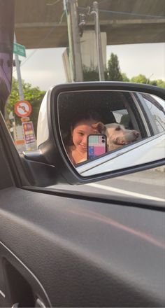 a woman taking a selfie in the side mirror of a car with her dog