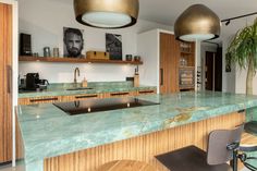 a kitchen with green marble counter tops and gold pendant lights over the sink, along with two chairs