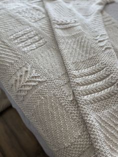 a white knitted blanket sitting on top of a bed