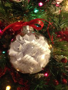 a christmas ornament hanging from the top of a tree covered in sheet music