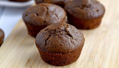 three chocolate muffins sitting on top of a wooden cutting board