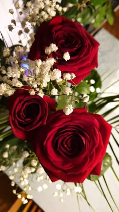 three red roses and white flowers in a vase