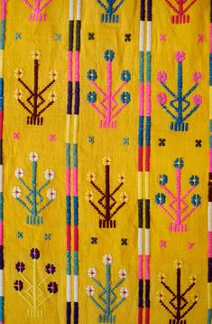 an embroidered yellow cloth with colorful designs on it's sides and flowers in the center