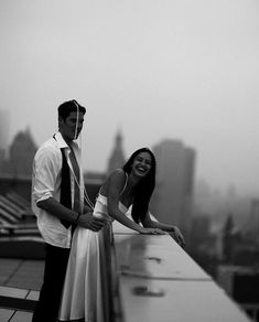 a man standing next to a woman on top of a building