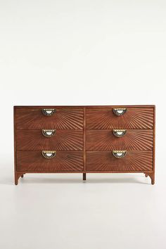 a wooden dresser with four drawers and three bowls on the bottom drawer, against a white background