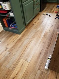 a kitchen floor that has been installed with wood floors and tools on the ground next to it