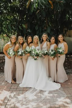 a group of women standing next to each other in front of a lush green tree