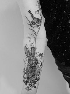 a black and white photo of a person with a rabbit tattoo on their arm