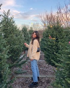 a woman standing in between rows of christmas trees