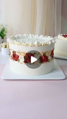 a cake with white frosting and red roses on it is sitting on a table