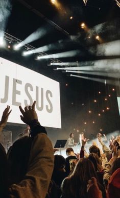 a large group of people standing on top of a stage with their hands in the air