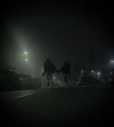 two people are walking down the street at night