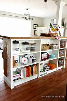 a white bookcase with lots of books on top of it next to a wooden floor