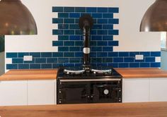 a stove top oven sitting inside of a kitchen next to two pendant lights on the wall