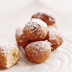 powdered sugar covered doughnuts on a white plate