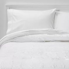 an unmade bed with white sheets and pillows