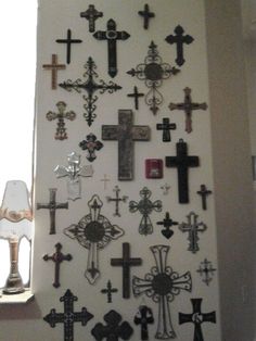 a wall with many crosses on it and a lamp in the corner next to it