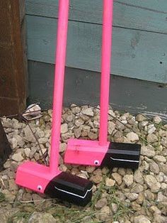 two pink plastic shovels sitting on top of some rocks