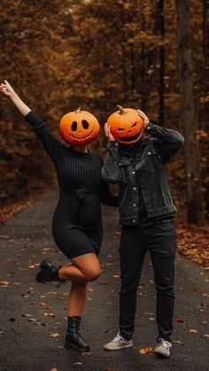 two people wearing pumpkin heads standing on a road