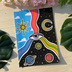 a card with an image of the sun, moon and planets on it next to some flowers