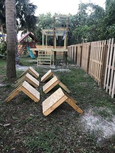 several pieces of wood laying on the ground in front of a wooden fence and swing set