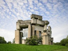 an unusual building sitting on top of a lush green hillside