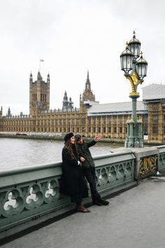 two people standing on a bridge looking at the clock tower in the distance with big ben in the background