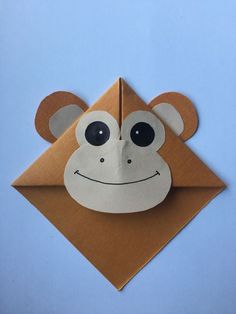 an origami monkey head on top of a piece of brown paper with black eyes