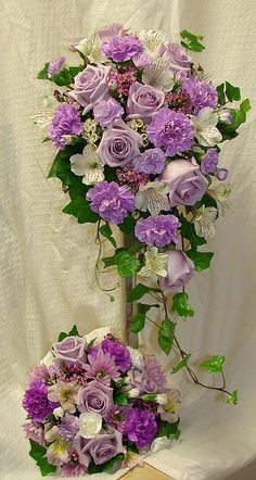 purple and white flowers are arranged in a tall vase