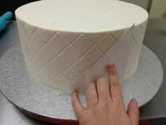 a person touching the top of a white cake