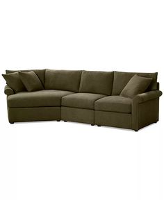 a large sectional couch with pillows on the top and bottom corner, in dark green