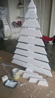 a wooden christmas tree sitting on top of a table next to a paint can and brush