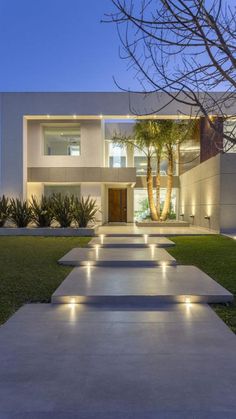 a modern house with lights on the walkway leading up to it's front door