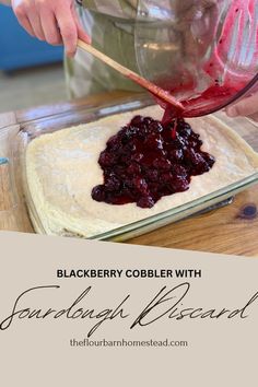 a person pouring cranberry cobbler with flour in a glass bowl on top of a wooden table