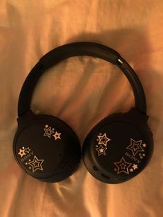 black headphones with gold stars on them sitting on a white sheeted bed top