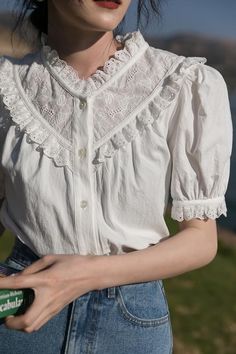 a woman wearing a white blouse and jeans holding a green bottle in her right hand