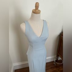 a mannequin wearing a blue dress on a wooden floor next to a white wall