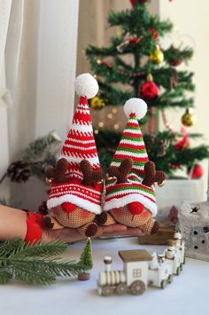 two knitted christmas trees sitting on top of a table next to a toy train