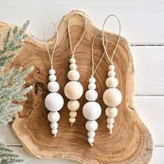 three wooden beads are hanging on a piece of wood next to a pine tree branch